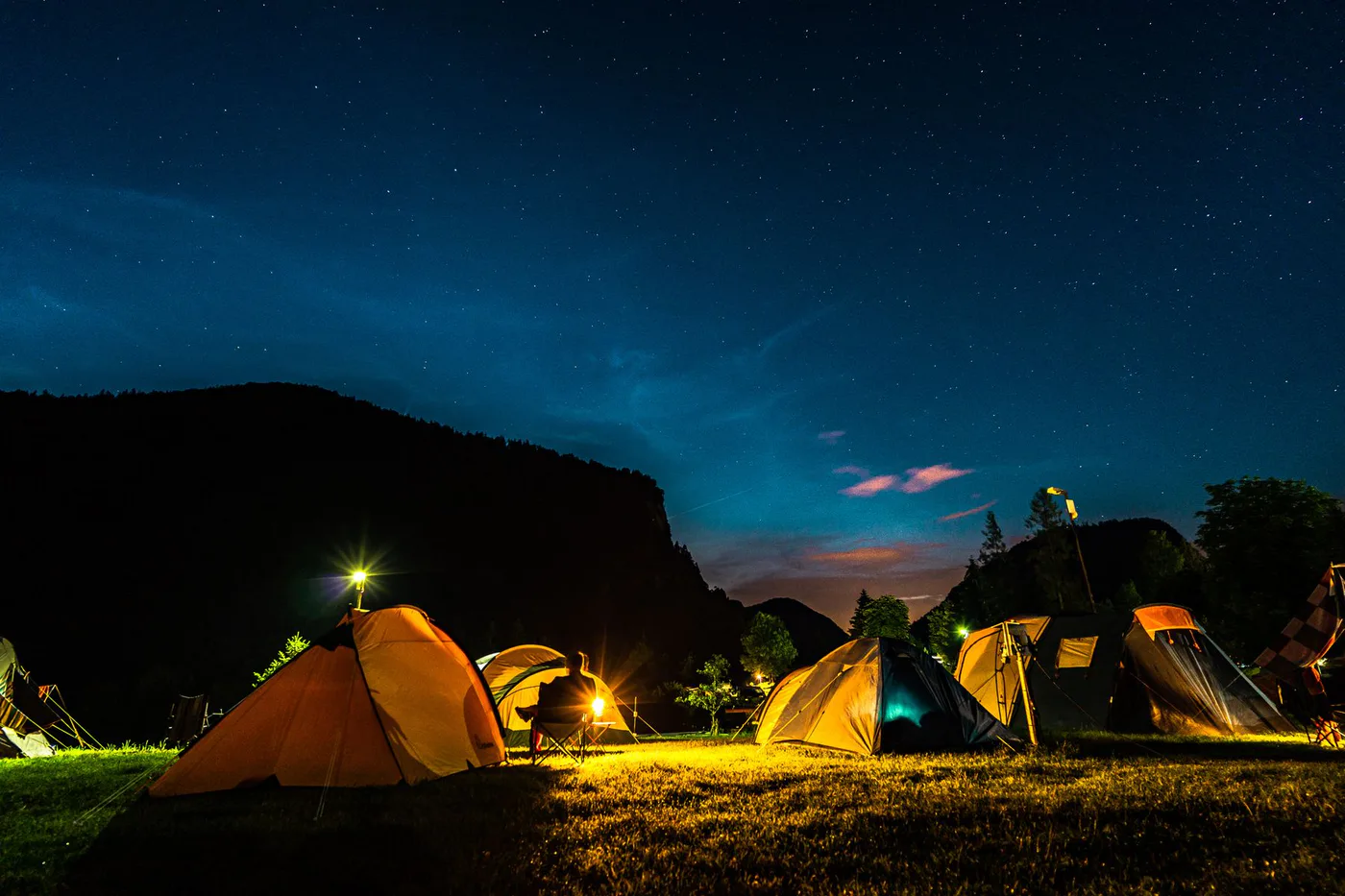 Illuminated tents below a starry mountain sky