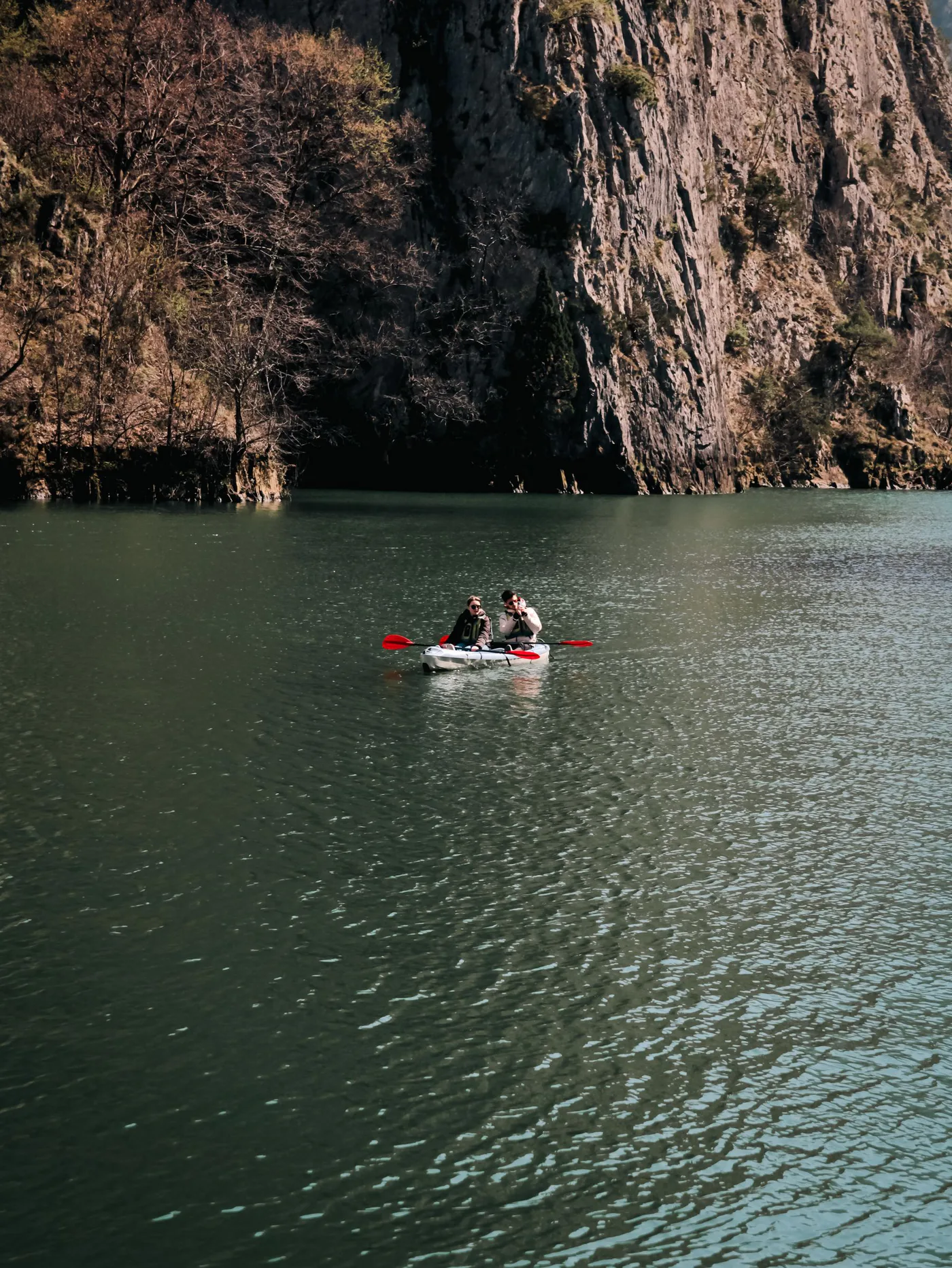Travellers kayaking across a calm mountain lake